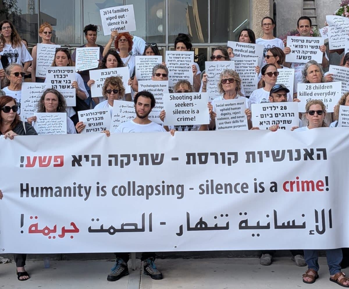פעילים מחזיקים שלטים בעברית, אנגלית וערבית: 'האנושיות קורסת — שתיקה היא פשע'